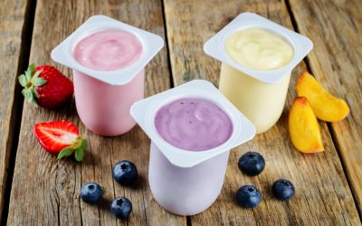 Variation of fruit yoghurts: strawberry, blueberry and peach on a wood background